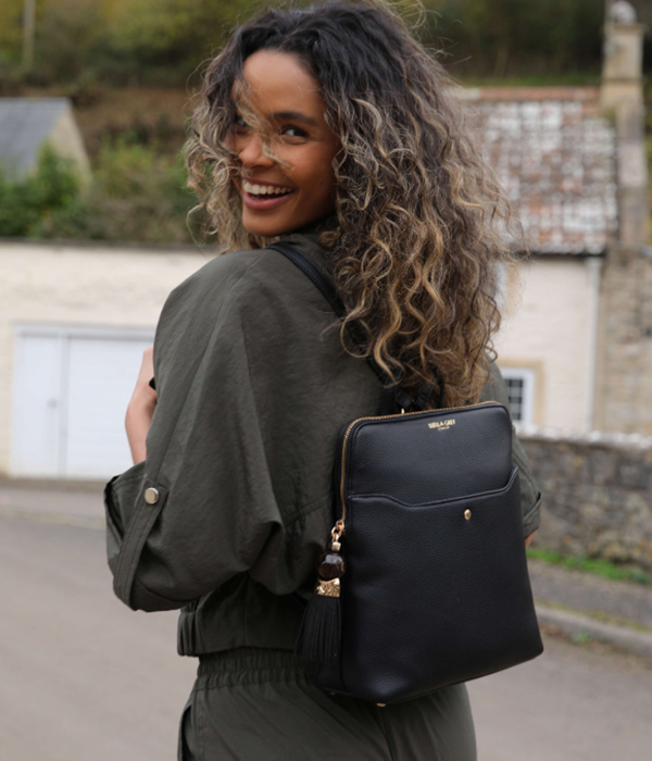 Woman with curly hair wearing a black backpack outdoors.