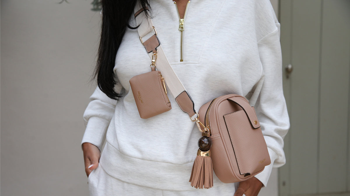 Model wearing casual atheleisurewear with a mocha crossbody bag with clip on charm purse and thames tassel charm