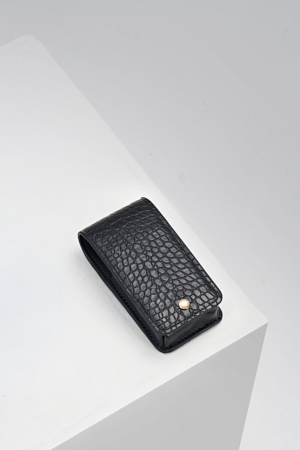 Aisling Black crocodile print faux leather Lipstick Holder with gold mag dot closure detail on the front displayed on a white plinth