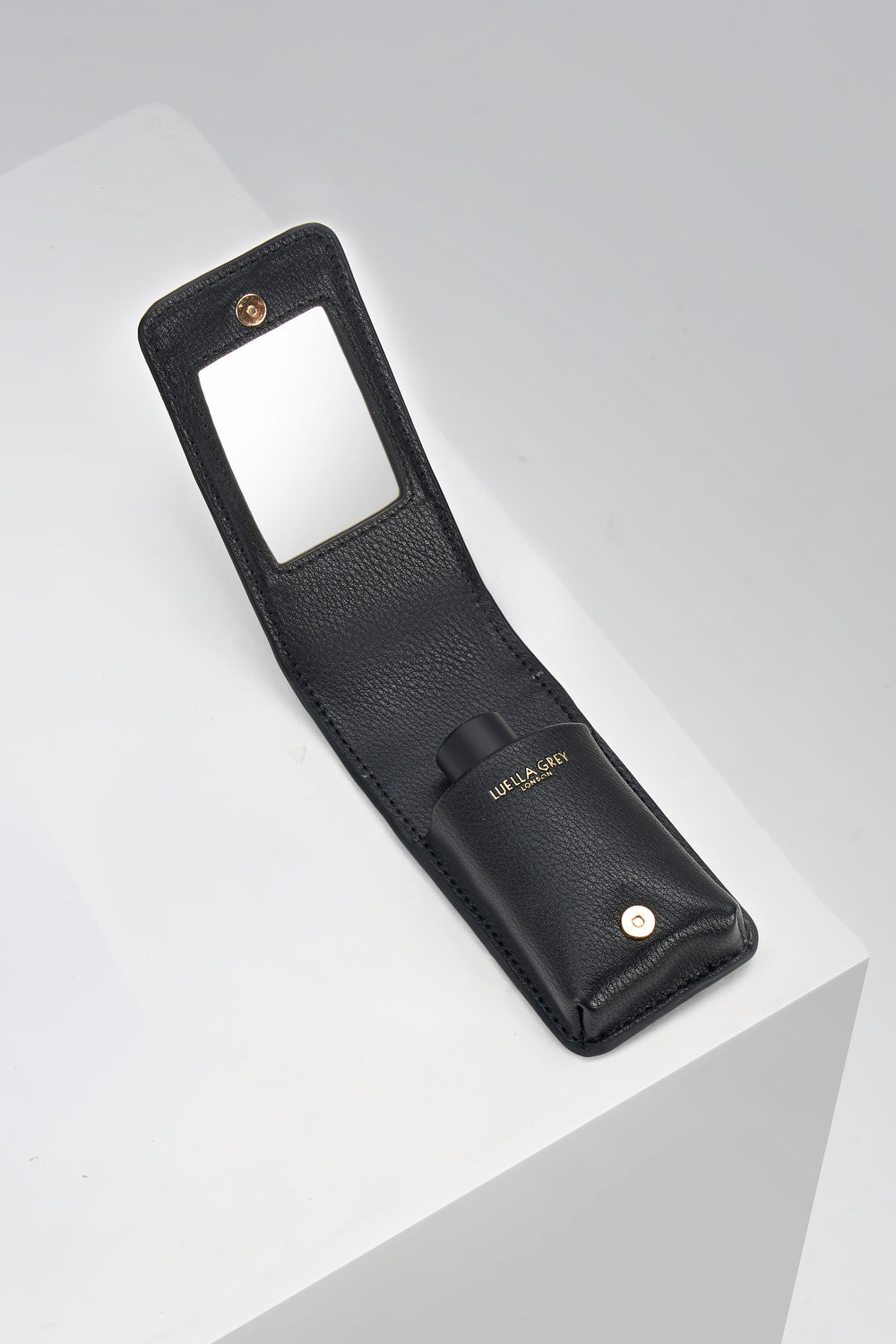 Inside of Aisling Black crocodile print faux leather Lipstick Holder showing a pocket for lipsticks and a mirror on the flap displayed on a white plinth
