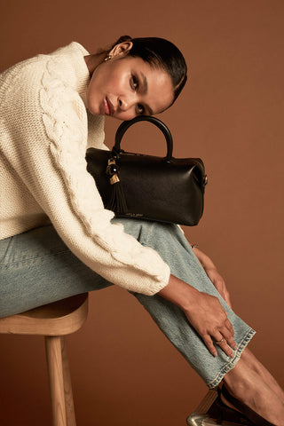 Female model with Alessia Black faux leather Bowler Tote by Luella Grey placed on her lap