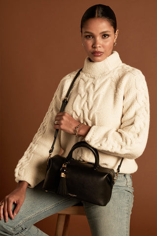 Female model wearing Alessia Black faux leather Bowler Tote by Luella Grey across her body using the detachable crossbody strap 