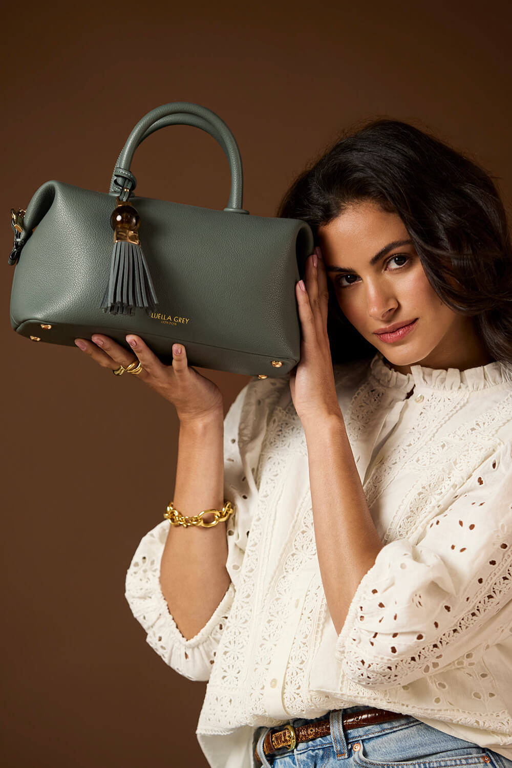 Female model holding the bottom and side of Alessia Steel Green faux leather Bowler Tote by Luella Grey showing the front of the bag