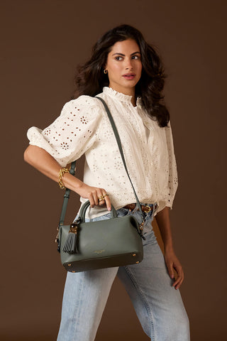 Female model wearing Alessia Steel Green faux leather Bowler Tote by Luella Grey across one shoulder using the detachable cross body strap