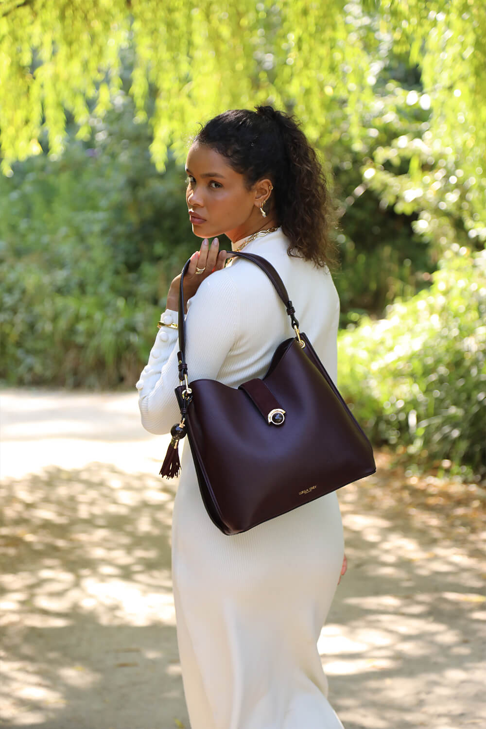 Female model holding Andrea Black Cherry faux leather Hobo shoulder bag over her shoulder
