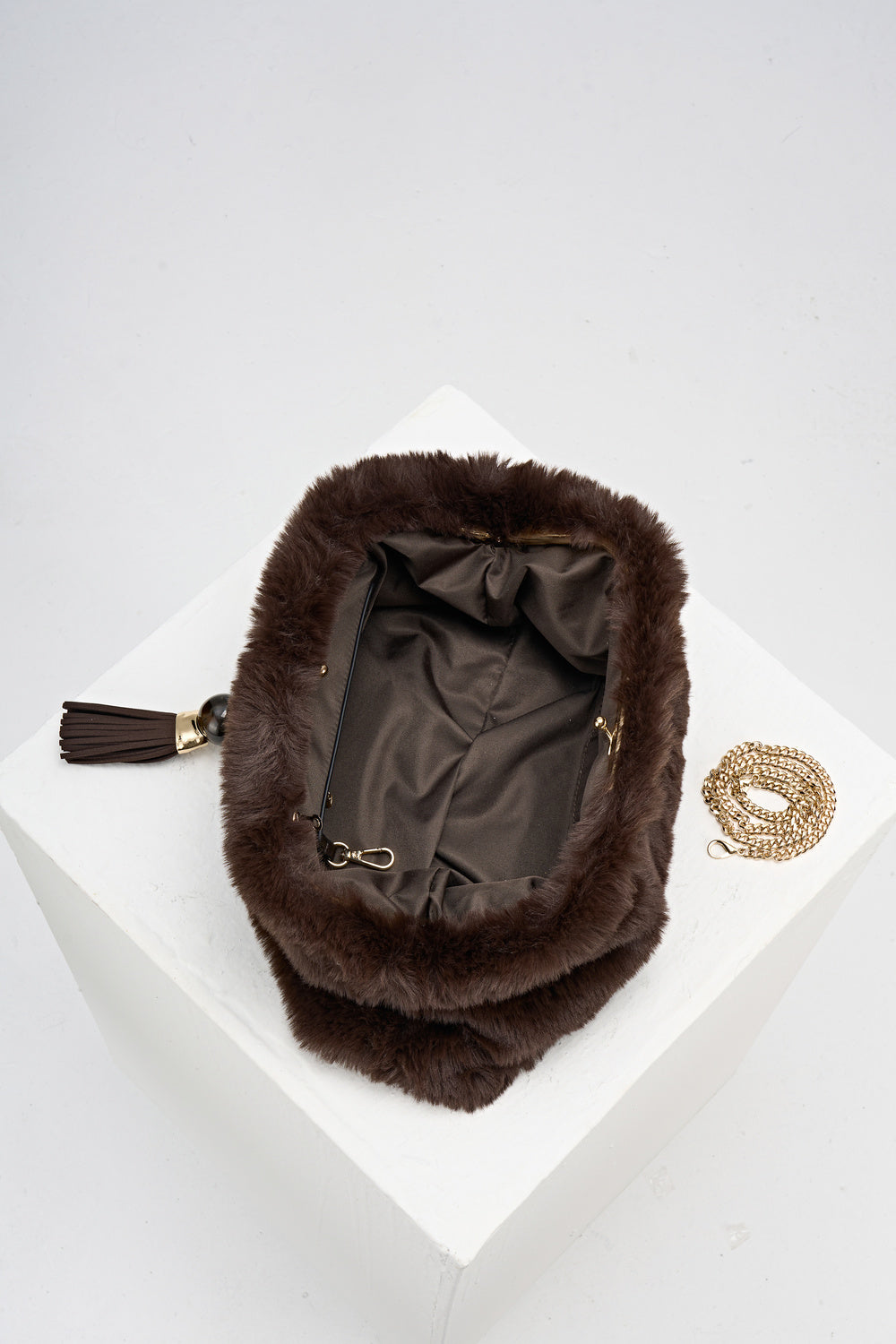 Overhead view of Indigo Chocolate faux fur Oversized Clutch open showing the inside and covered gold frame clasp opening and the gold metal chain next to the bag