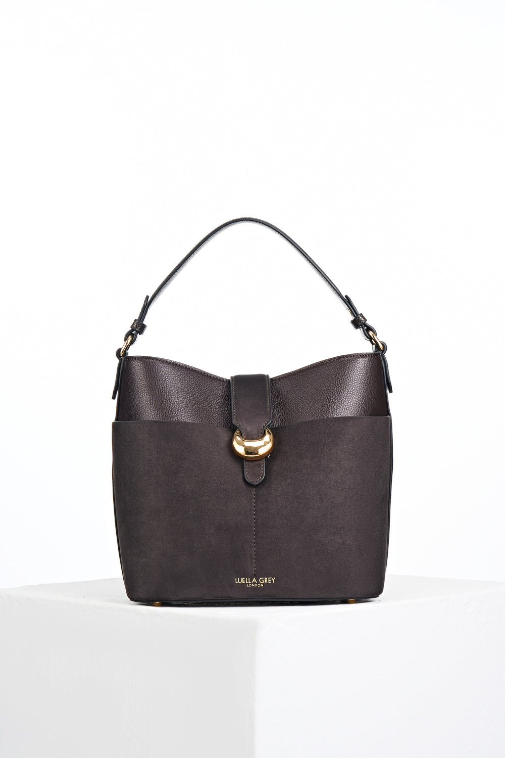 Front of Indra Chocolate recycled suede and faux leather Bucket Crossbody showing the Signature Molten Metal Cannon Street Clasp closure on the front slip in suede pocket