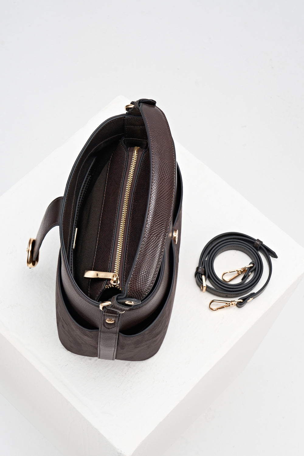 Overhead view of Indra Chocolate recycled suede and faux leather Bucket Crossbody showing the internal pockets and the detachable crossbody strap next to the bag