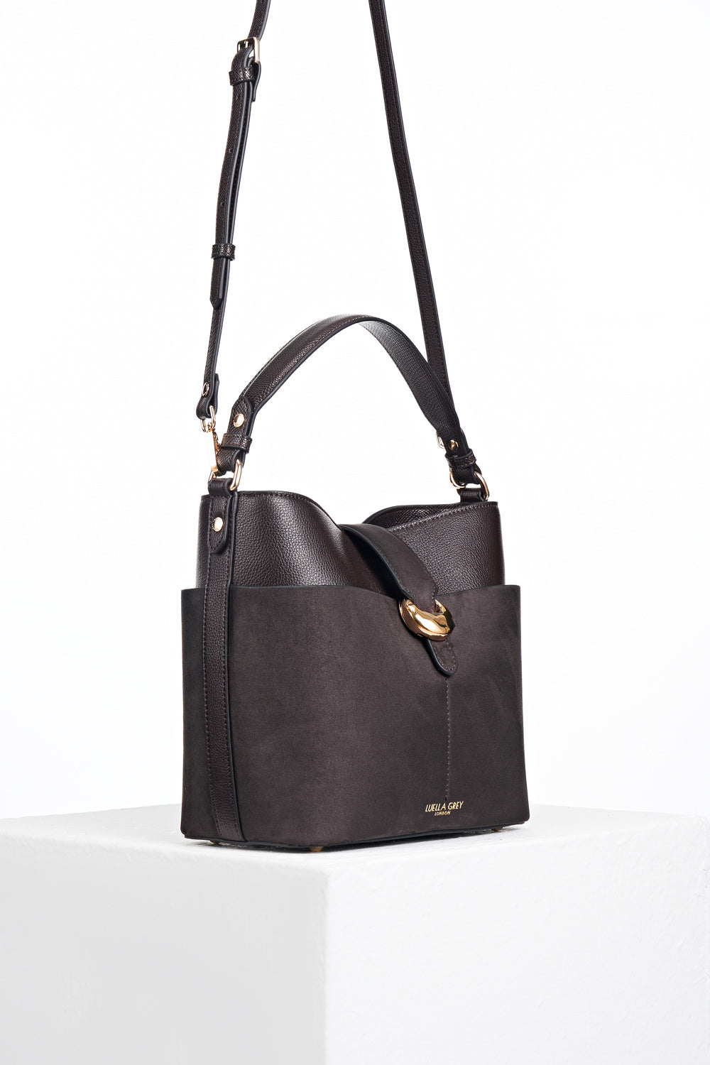 Side view of Indra Chocolate recycled suede and faux leather Bucket Crossbody with the detachable crossbody strap attached to the gold rings on the side of the bag