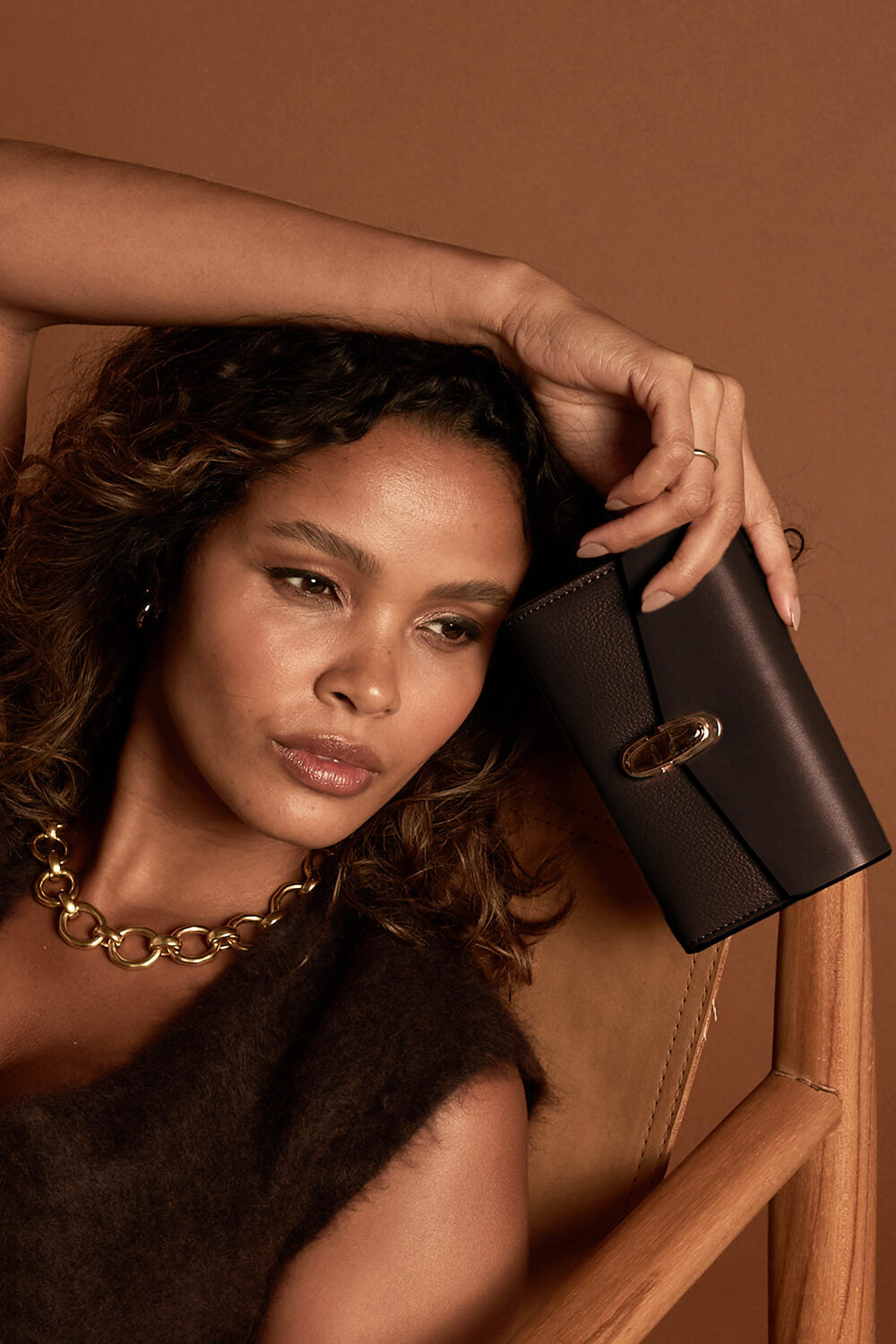 Female model holding Leontina Chocolate Medium Purse in one hand