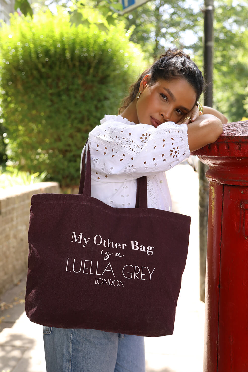 Female model wearing Luella Cherry Canvas Shopper with printed white writing details over her shoulder with two shoulder straps