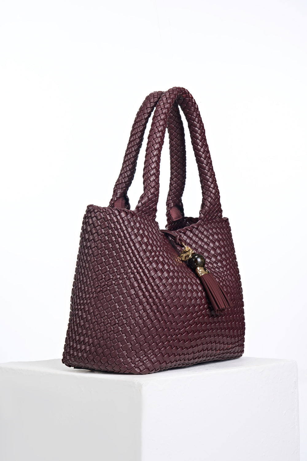 Side view of Saskia Black Cherry faux leather Woven Tote with Thames Tassel closure detail