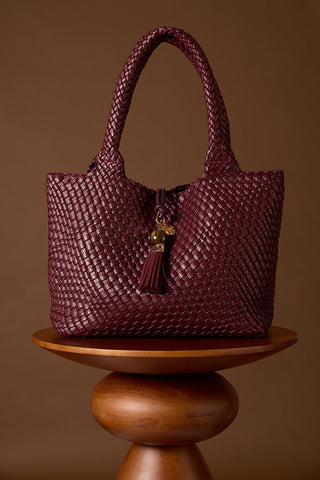 Saskia Black Cherry faux leather Woven Tote on a brown wooden plinth