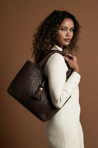 Female model wearing Saskia Chocolate faux leather Woven Tote over her shoulder with the two shoulder handles
