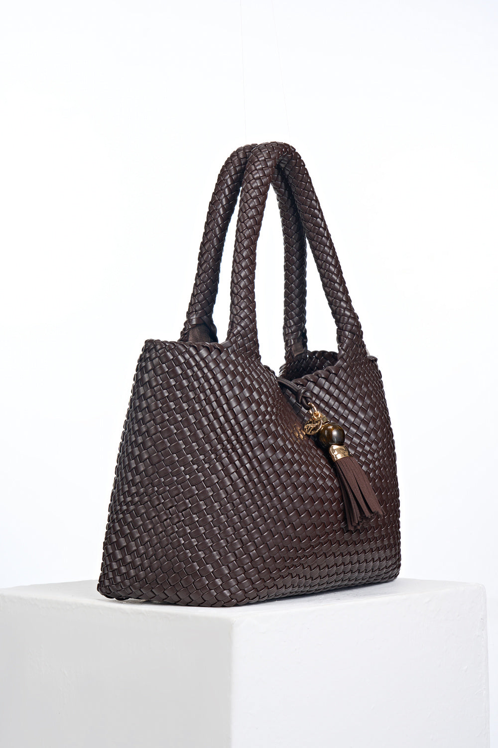 Side view of Saskia Chocolate faux leather Woven Tote with Thames Tassel closure detail