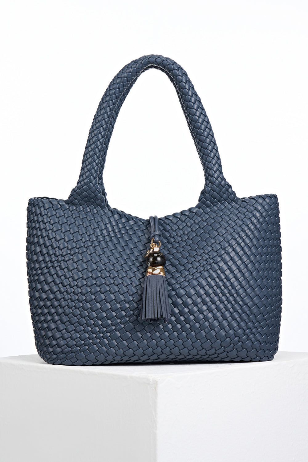 Front view of Saskia Denim Blue faux leather Woven Tote with Thames Tassel closure detail