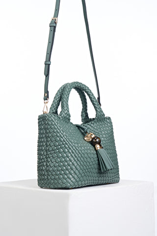 Side view of Suky Steel Green faux leather Woven Crossbody with detachable crossbody strap attached to gold rings on the bag's side
