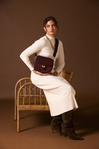 Female model wearing Venetia Black Cherry Faux leather Saddle Crossbody across her body