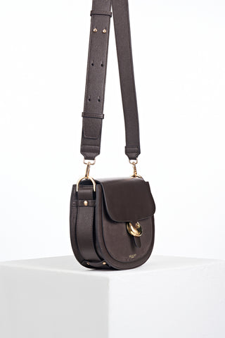 Side view of Venetia Chocolate Faux leather Saddle Crossbody showing the strap detailing around the bottom of the bag and Cannon Street Clasp detail on the front