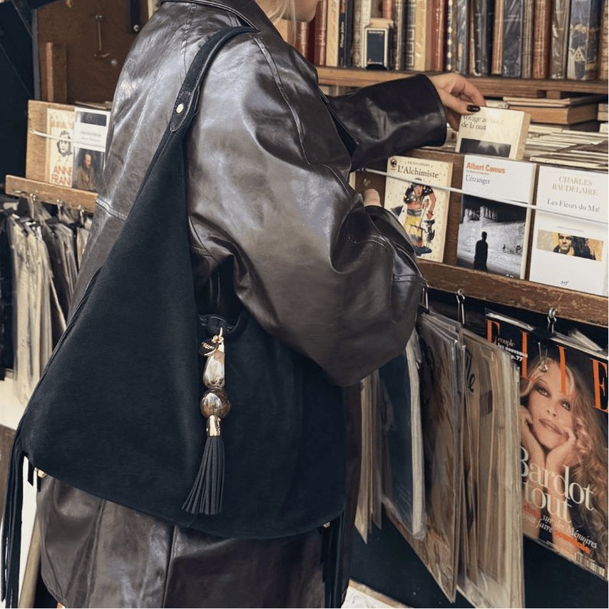 Person browsing records in a store with a black leather jacket and bag.